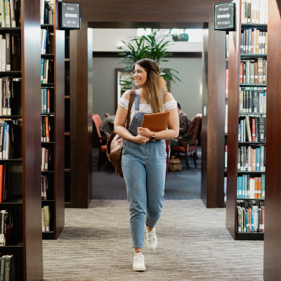 student walking through stacks of Payson Library