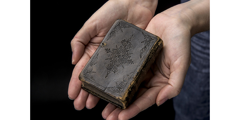 Two hands holding small book.