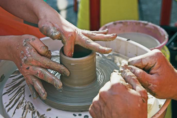 artist's hands throwing a vessel on a potter's wheel