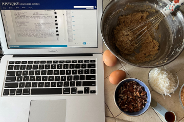 Image of laptop open to recipes next to ingredients on kitchen table.