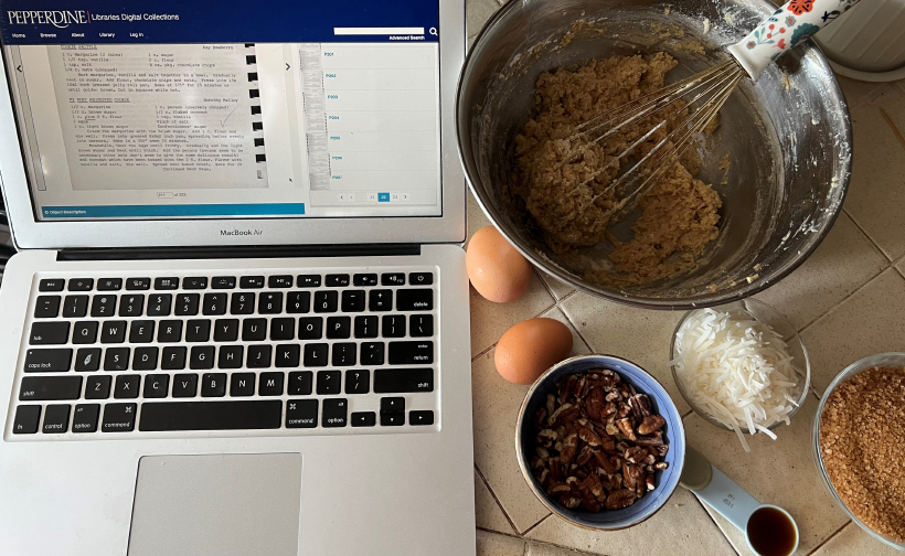 Laptop open to recipes next to ingredients on kitchen table.