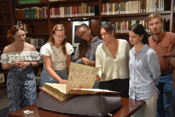 students flipping through old manuscript