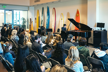 Student performing in front of packed house in the Surfboard Room